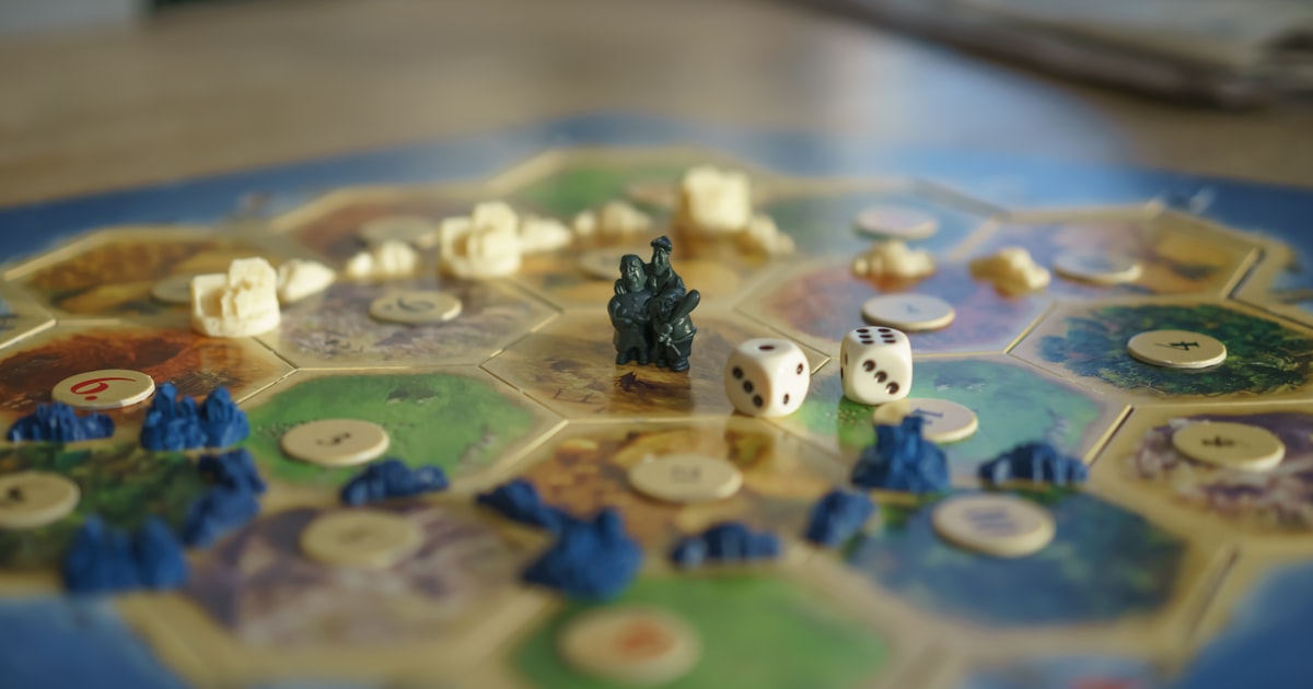 A table with various modern board games laid out, showing colorful components and engaged players