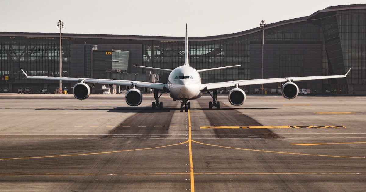 Airplane seat with travel essentials organized including noise-canceling headphones, travel pillow, and charging gear